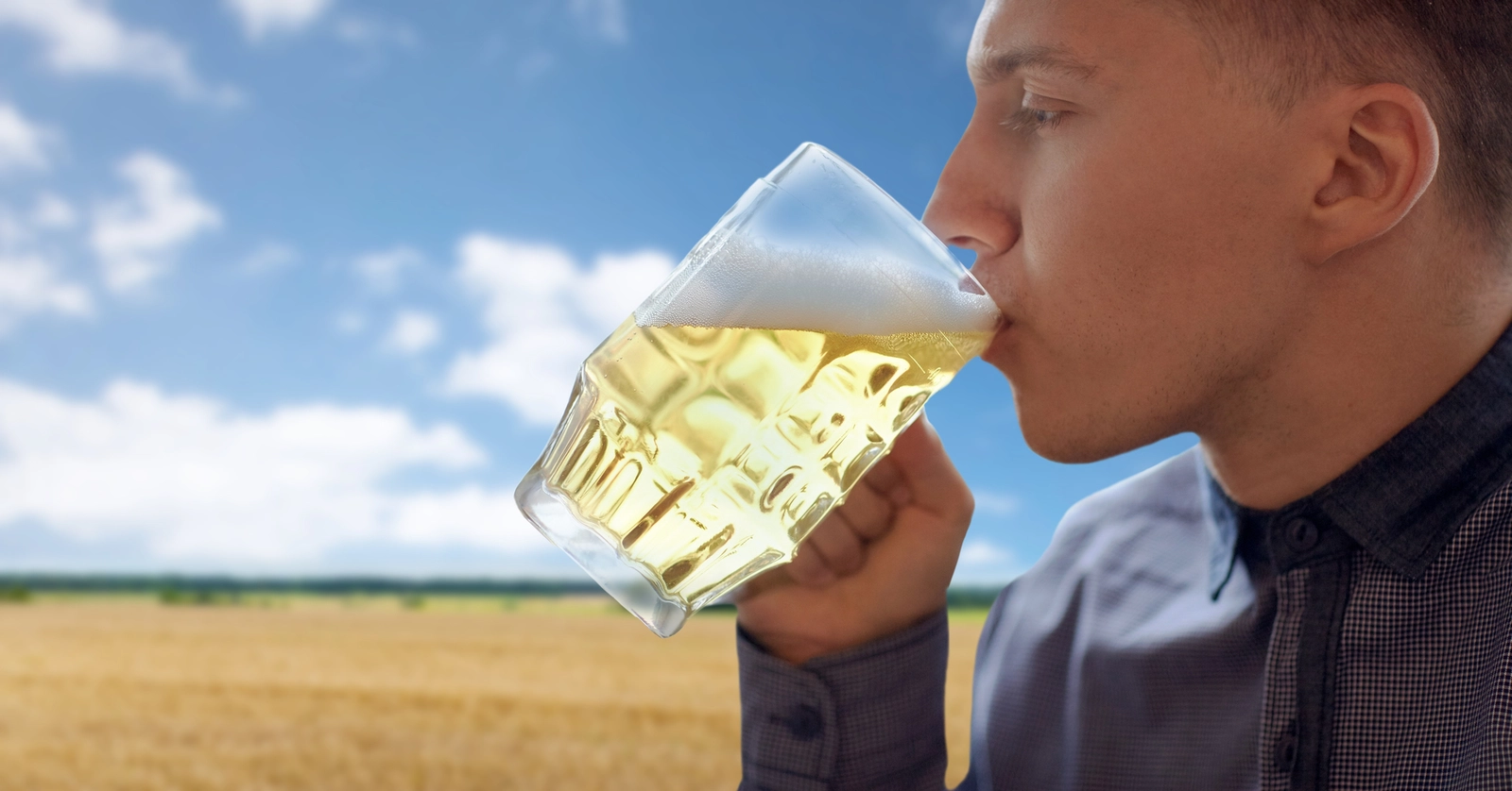 Accutane and Alcohol: A profile view of a man drinking a mug of beer outdoors.