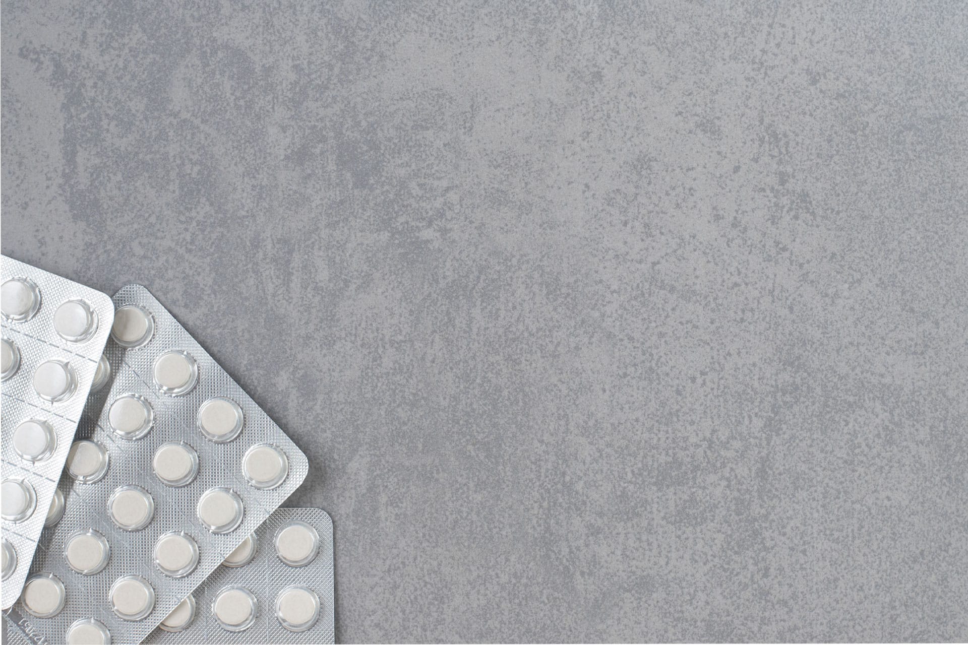 Low Dose Naltrexone Drug Interactions: A gray surface with white pills in three blister packs.