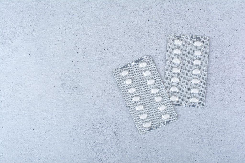 A gray surface with two blister packs containing white pills